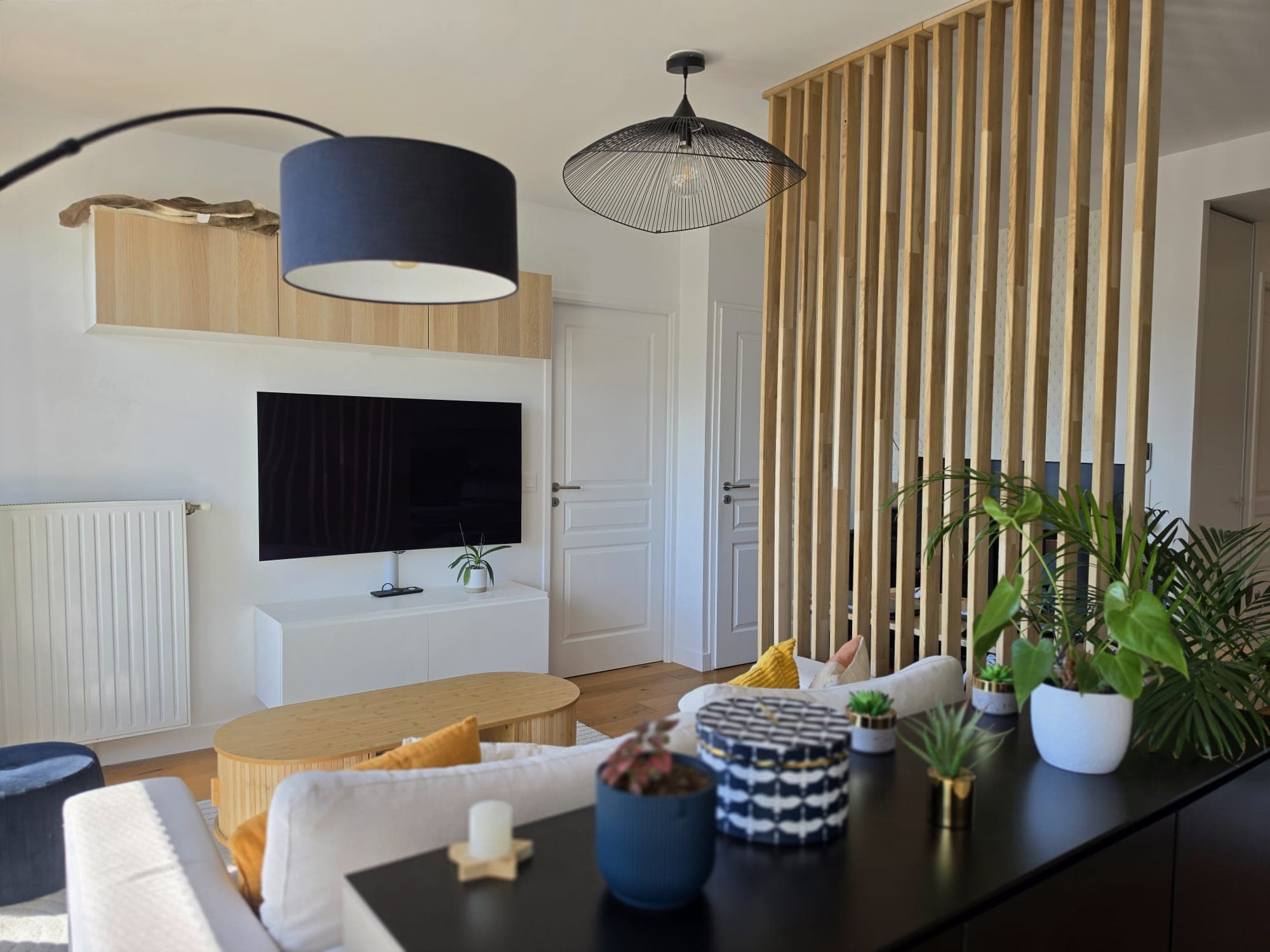 Salon avec meuble TV blanc, suspension en métal et claustra en bois